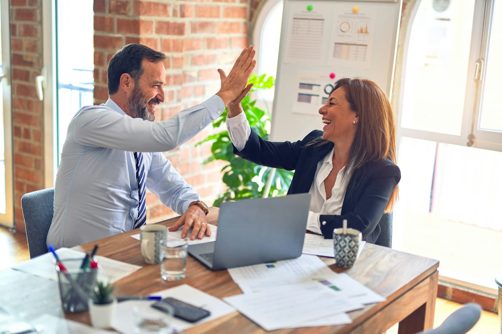 Twee collega's vieren een succes aan hun bureau