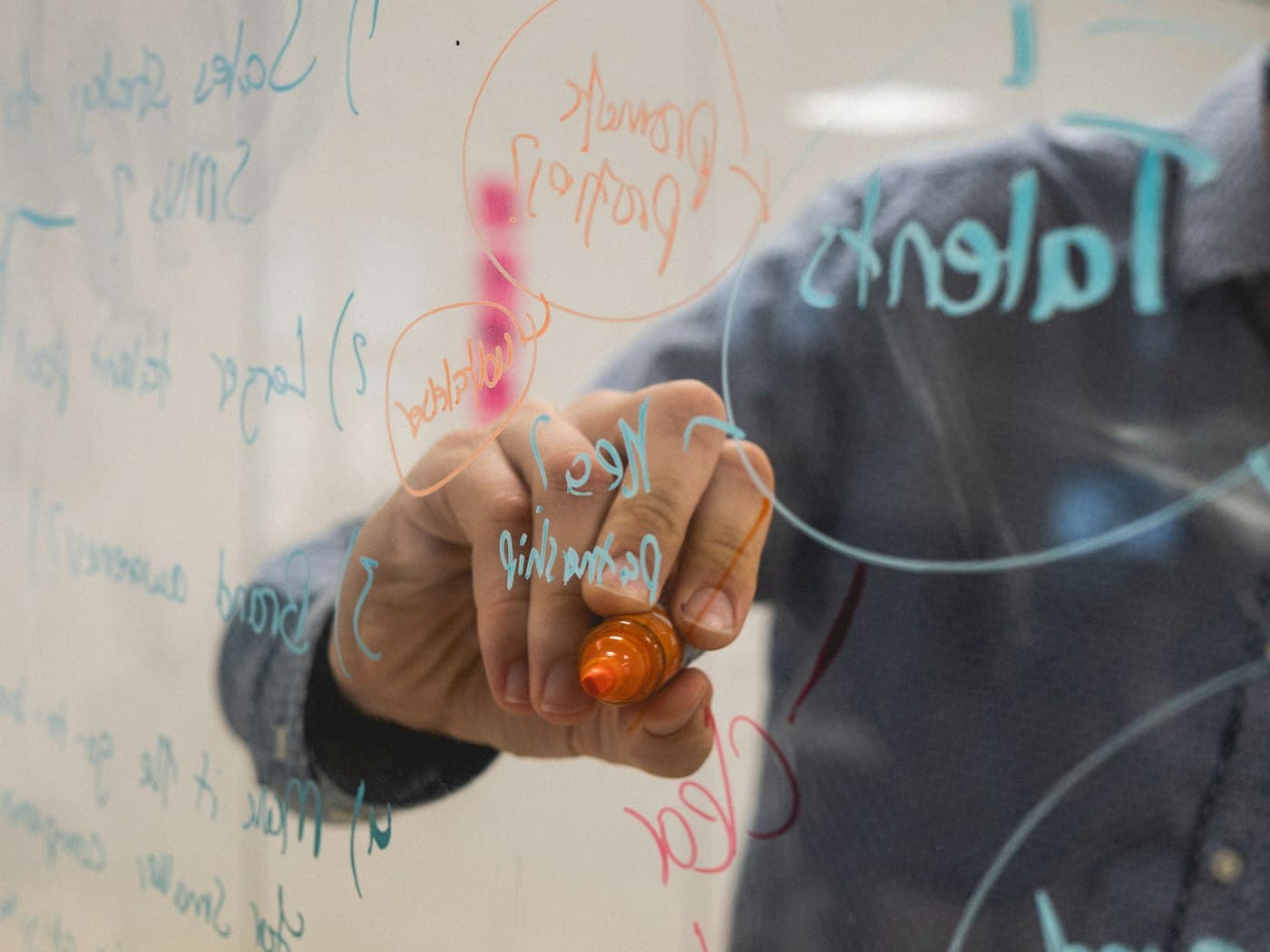 Iemand schrijft ideeën en schema's op een glazen whiteboard